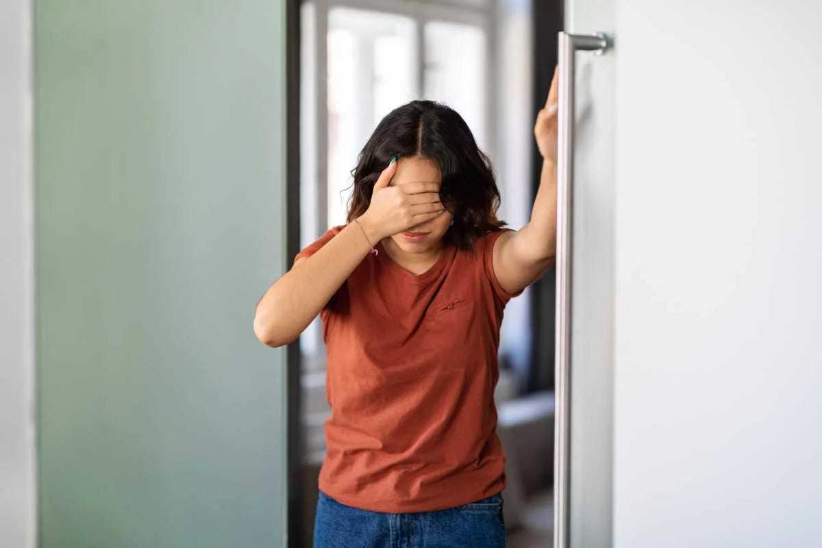 femme se tenant la tête et à un mur car elle est plein vertige dû au stress et à la fatigue