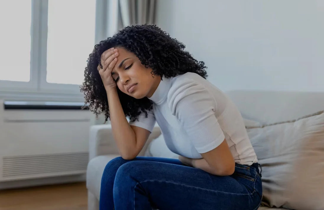 femme assise sur sur sont lit se tenant le venant à cause des symptomes des troubles digestifs liés au stress